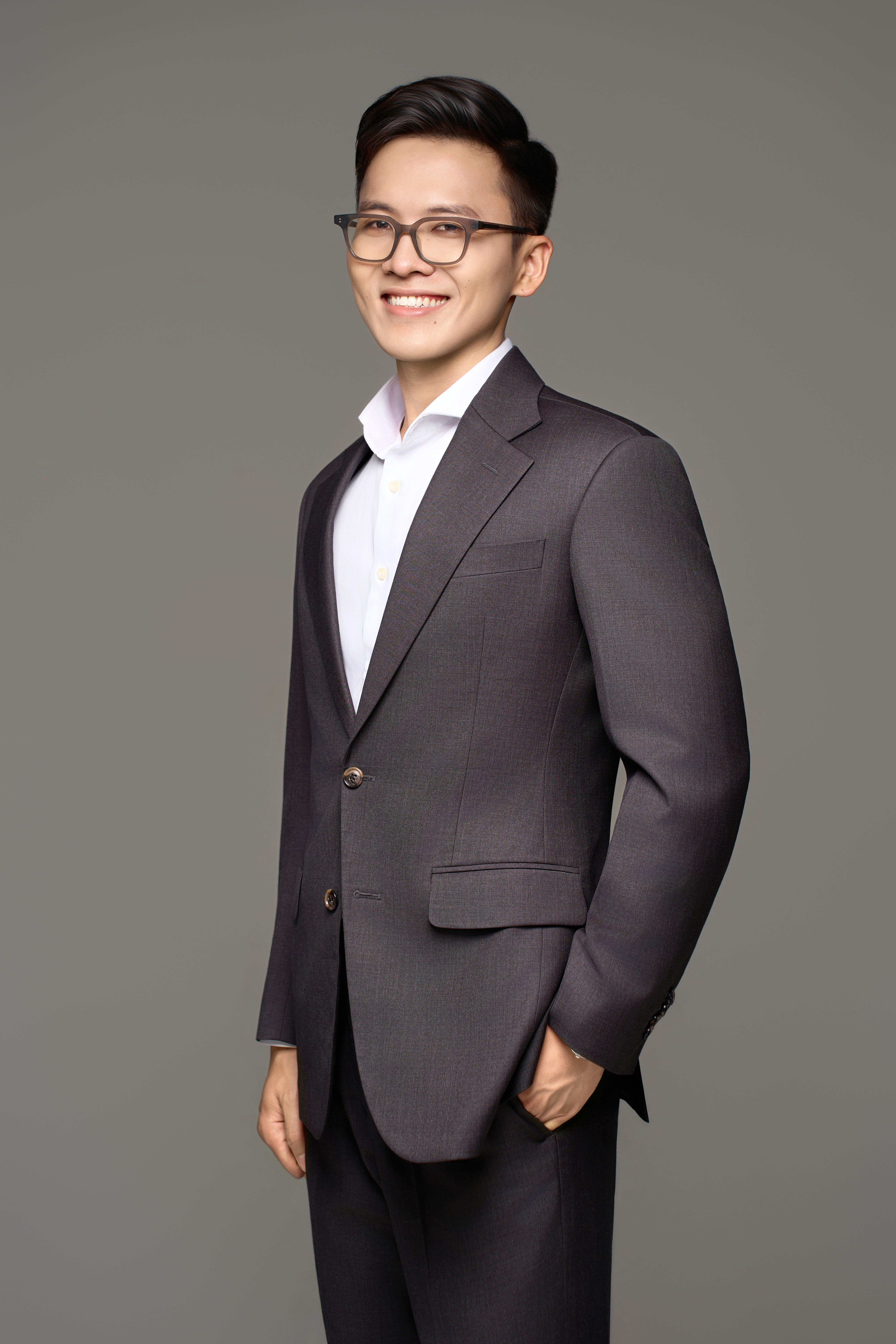 Smiling man wearing suit, with glasses, and short black hair styled to one side